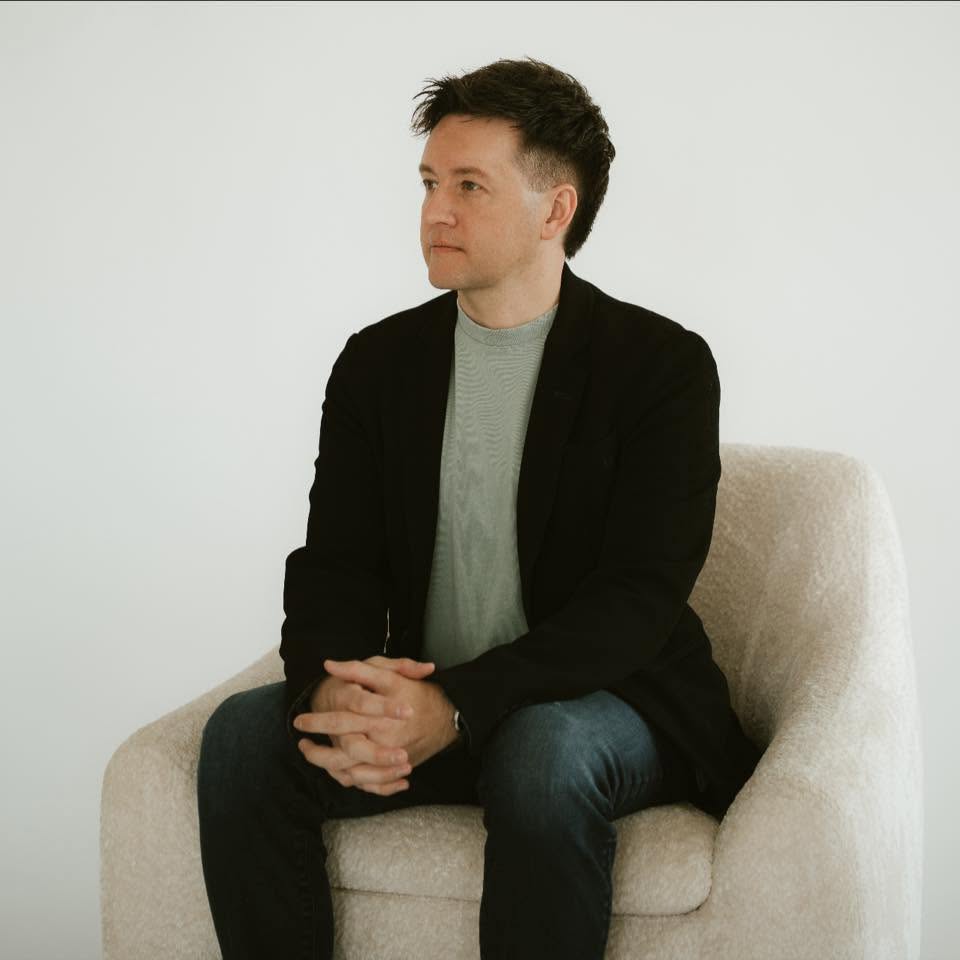 Cody Miller seated in a bouclé armchair in a calm, minimal room